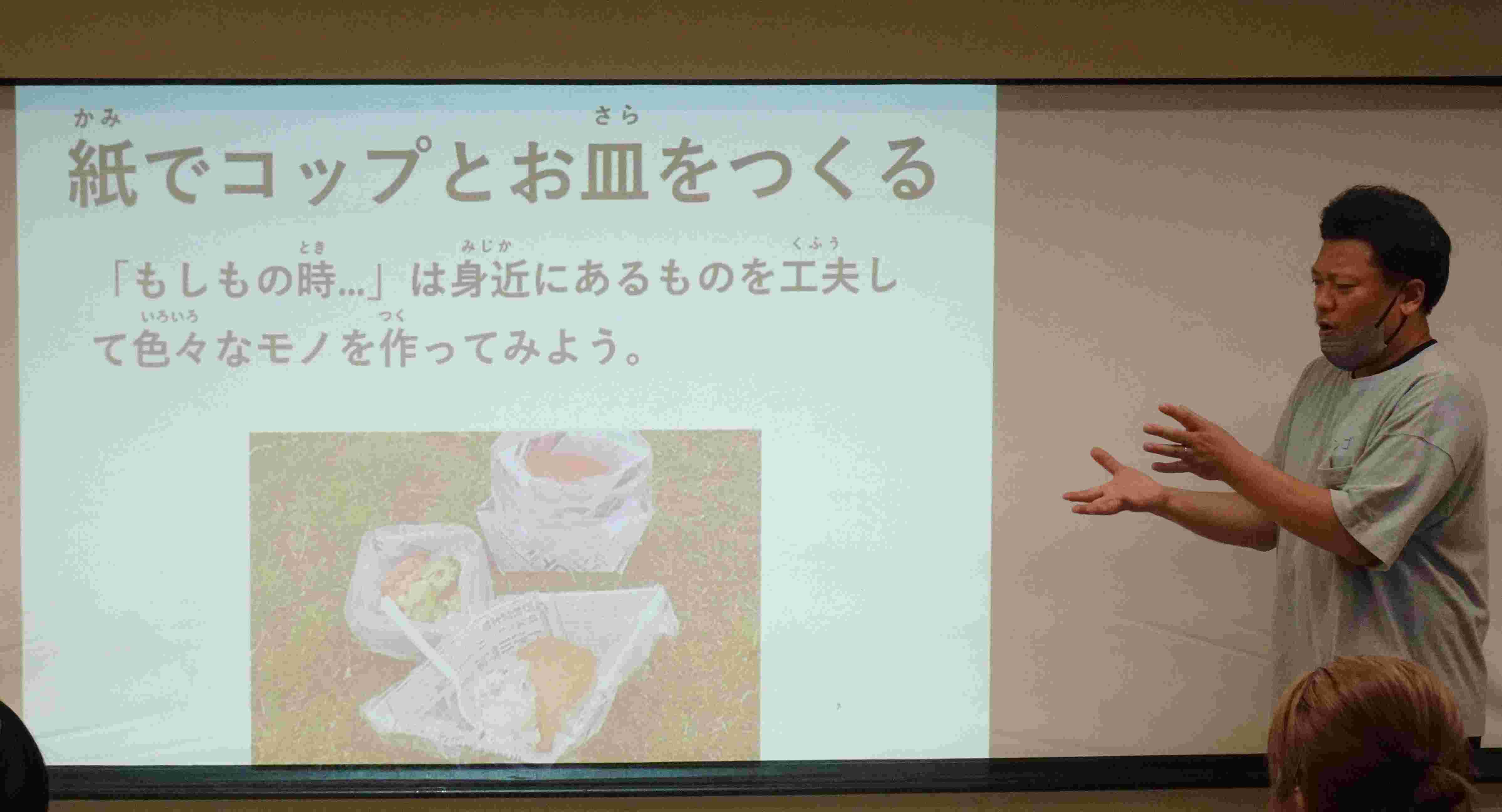 紙で作るコップを説明している様子